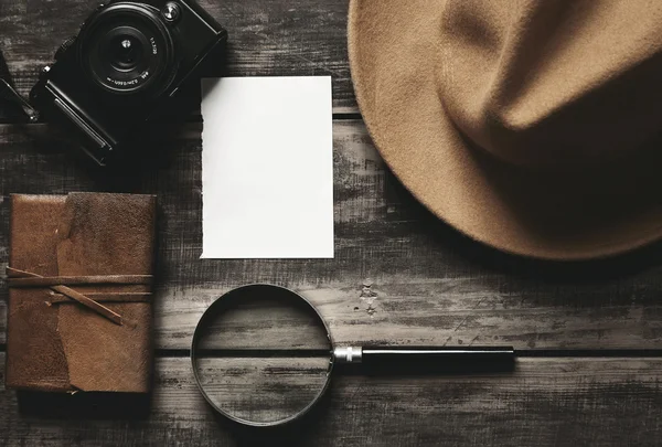 Cámara fotográfica, cuaderno, sombrero, lupa, papel sobre mesa negra —  Fotos de Stock