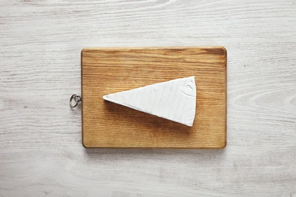 Brie isolated on cutting board on white table — Stock Photo, Image