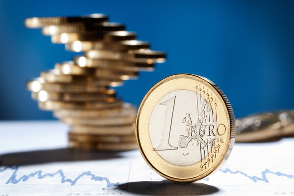Euro coin with a stack of coins in the background
