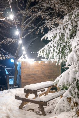 Büyüleyici manzara, kışın inanılmaz bir Noel havası yaratır. Kabarık bir ladin ağacı ve ahşap kulübenin yanında masası olan bir bank, her şey yumuşak karla kaplanmış ve çelenklerin ışığıyla aydınlanmış.