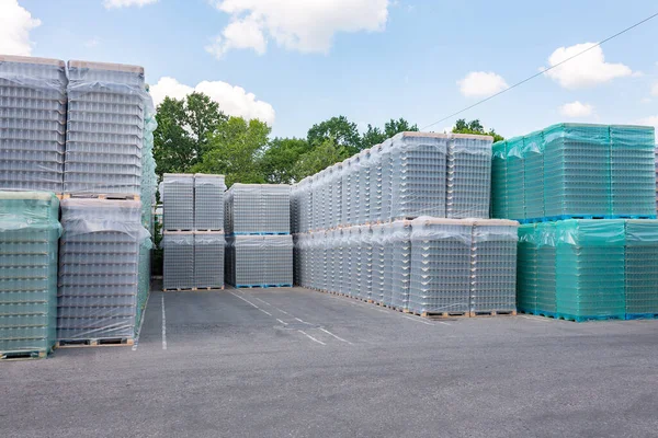 The open air storage and carriage of the finished product at industrial facility. A glass clear bottles for alcoholic or soft drinks beverages and canning jars stacked on pallets for forklift.