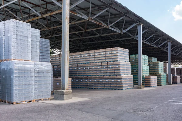 The open air storage and carriage of the finished product at industrial facility. A glass clear bottles for alcoholic or soft drinks beverages and canning jars stacked on pallets for forklift.