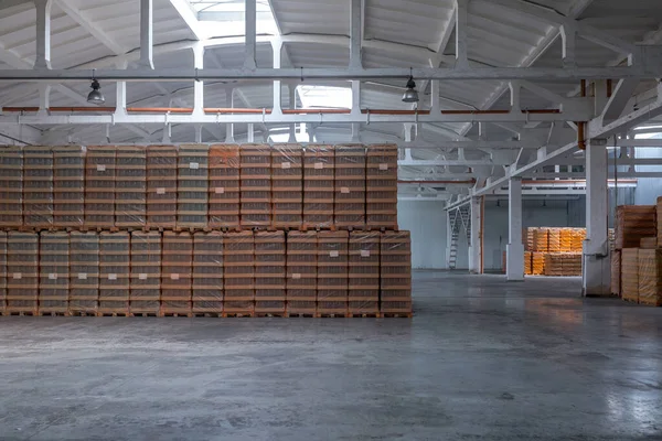The storage and carriage at industrial food industry facility. A glass clear bottles for alcoholic or soft drinks beverages and canning jars stacked on pallets for forklift.