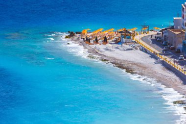 Boş bir sahil beldesinde renkli şemsiyeler ve güneşlikler - Ege ve Akdeniz 'deki Yunanistan adalarında tatil kavramı. Rodos 'taki Elli Plajı.