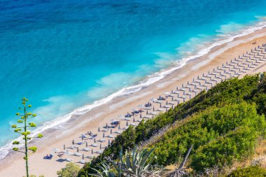 Boş bir sahil beldesinde renkli şemsiyeler ve güneşlikler - Ege ve Akdeniz 'deki Yunanistan adalarında tatil kavramı. Rodos 'ta Monte Smith' in altında Akti Kanari Plajı.