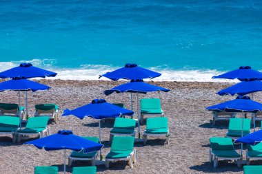 Boş bir sahil beldesinde renkli şemsiyeler ve güneşlikler - Ege ve Akdeniz 'deki Yunanistan adalarında tatil kavramı