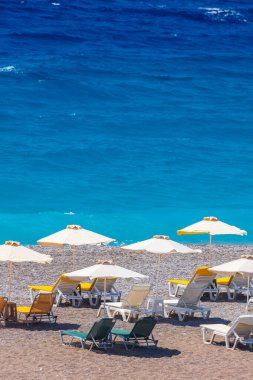 Boş bir sahil beldesinde renkli şemsiyeler ve güneşlikler - Ege ve Akdeniz 'deki Yunanistan adalarında tatil kavramı