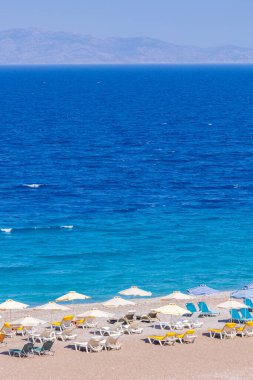 Boş bir sahil beldesinde renkli şemsiyeler ve güneşlikler - Ege ve Akdeniz 'deki Yunanistan adalarında tatil kavramı