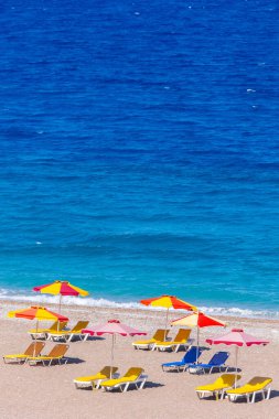 Boş bir sahil beldesinde renkli şemsiyeler ve güneşlikler - Ege ve Akdeniz 'deki Yunanistan adalarında tatil kavramı