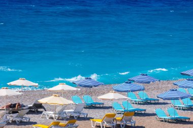 Boş bir sahil beldesinde renkli şemsiyeler ve güneşlikler - Ege ve Akdeniz 'deki Yunanistan adalarında tatil kavramı