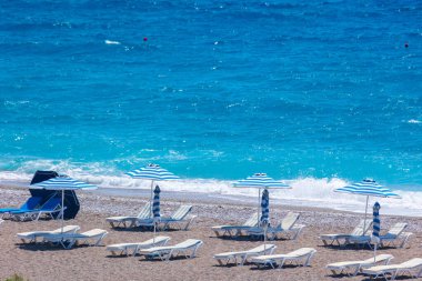 Boş bir sahil beldesinde renkli şemsiyeler ve güneşlikler - Ege ve Akdeniz 'deki Yunanistan adalarında tatil kavramı