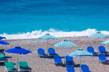 Boş bir sahil beldesinde renkli şemsiyeler ve güneşlikler - Ege ve Akdeniz 'deki Yunanistan adalarında tatil kavramı