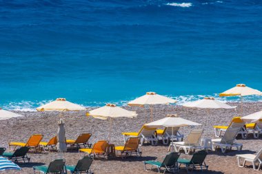 Boş bir sahil beldesinde renkli şemsiyeler ve güneşlikler - Ege ve Akdeniz 'deki Yunanistan adalarında tatil kavramı