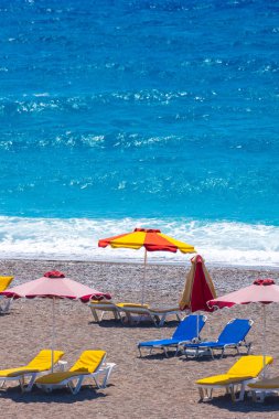 Boş bir sahil beldesinde renkli şemsiyeler ve güneşlikler - Ege ve Akdeniz 'deki Yunanistan adalarında tatil kavramı