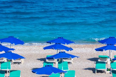 Boş bir sahil beldesinde renkli şemsiyeler ve güneşlikler - Ege ve Akdeniz 'deki Yunanistan adalarında tatil kavramı