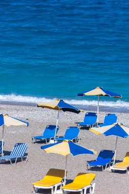 Boş bir sahil beldesinde renkli şemsiyeler ve güneşlikler - Ege ve Akdeniz 'deki Yunanistan adalarında tatil kavramı