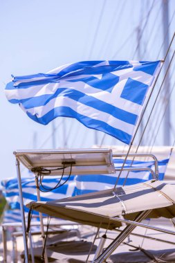 Yelkenli yatların kıçında Yunan bayrakları dalgalanır. Limanda, güzel yaz güneşli havalarda. Akdeniz kıyıları Yunanistan, Dodecanese, Rodos Adası.