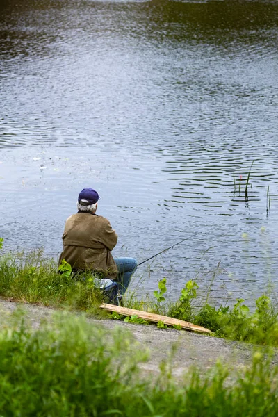 Fishing as a hobby. A man fishing with a fishing rod on the shore of a pond, river or lake, will spend his free time.