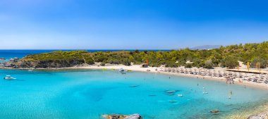 Glystra sahilinde kristal berrak turkuaz su. Ege ve Akdeniz 'deki Yunanistan adalarında tatil konsepti olan bir sahil beldesinde bulunan kadife şemsiyeler ve güneşlikler. Doğu Rhodes 'da Lindos yakınlarında. Yunanistan