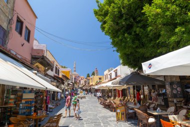 Rhodes, Yunanistan - 28 Haziran 2021: Sıcak yaz güneşli öğleden sonra turistik bir yer. Eski Rhodes Kasabası 'ndaki Sokrates Caddesi. Dükkanlar, restoranlar, yüzlerce turist ve tatilci..