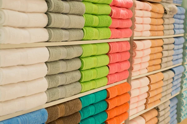 Красочные полотенца с плетеной корзиной на полке стеллажного фона — стоковое фото