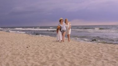 Güzel kız kardeşler kumsalda gülümseyen anneleriyle.