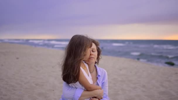 Madre feliz está abrazando al bebé en la playa al atardecer. — Vídeos de Stock