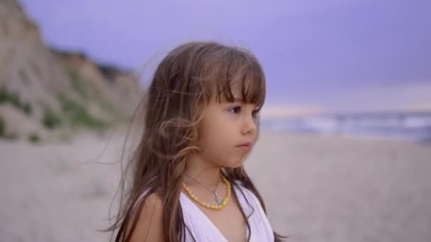 Entzückend glückliches kleines Mädchen in weißem Kleid 4-5 Jahre am weißen Strand bei Sonnenuntergang. — Stockvideo