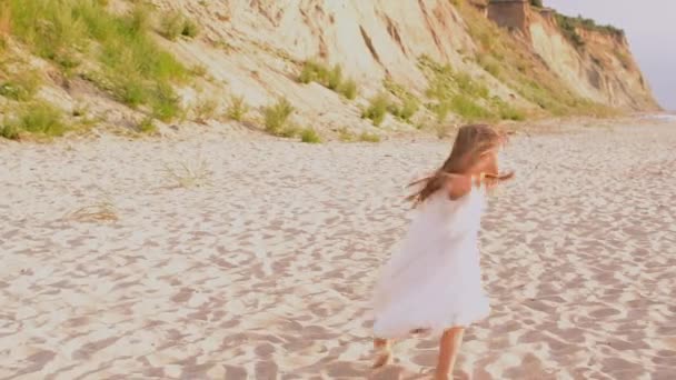 Adorable niña feliz en vestido blanco en la playa blanca al atardecer. — Vídeos de Stock