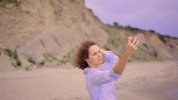 Nahaufnahme einer fröhlichen Frau im blauen Kleid, die ein Selfie am Strand macht. — Stockvideo