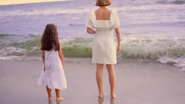 Glada unga flickor leker med vågorna på stranden. — Stockvideo