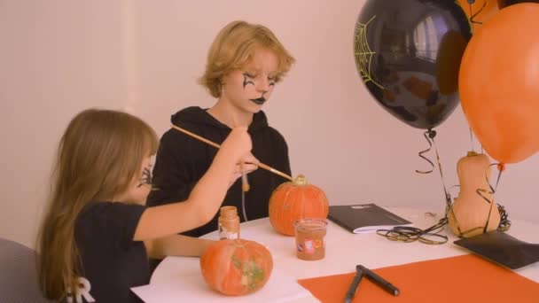 Leuke meisjes schilderen Halloween pompoenen — Stockvideo