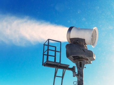 Kar topu yapay karı parlak mavi gökyüzüne püskürtür.