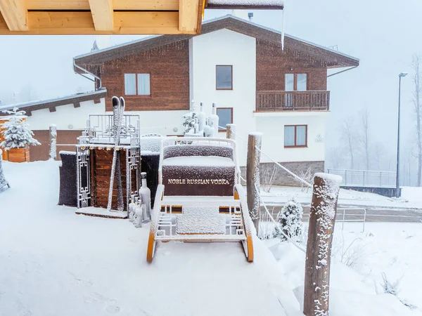 Ryssland, Sotji 22.01.2020. Dekorativa slädar, skidor och flaskor vodka strödda med snö står framför byggnaden. Reklamanläggning — Stockfoto