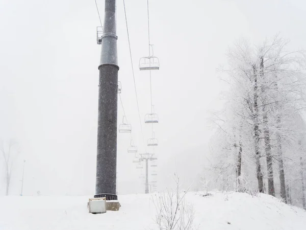 Порожній підйомний стілець в тумані в зимовий день під час снігопаду на фоні дерев — стокове фото