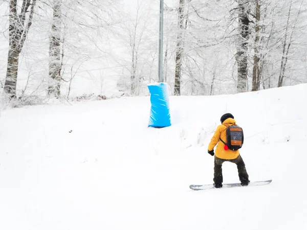 Snowboarder cavalca il sentiero lungo la foresta in una giornata nebbiosa — Foto Stock