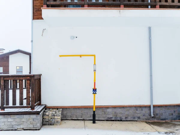 The yellow pipe adjoins the white wall of the house on the street — Stock Photo, Image