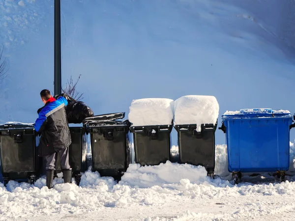 İşçi kışın karlı bir günde çöp kutusuna çöp atar — Stok fotoğraf