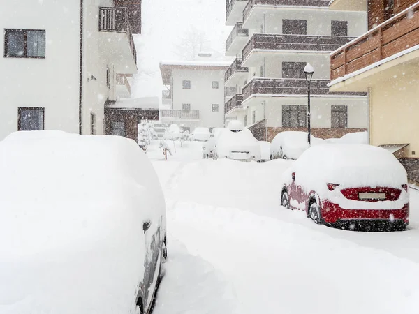 Snöströdda bilar står parkerade vid stugorna en snöig vinterdag. Skidanläggning — Stockfoto