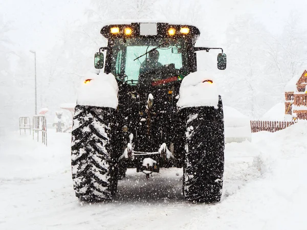 Tractor shovels snow from the road during heavy snowfall Royalty Free Stock Images
