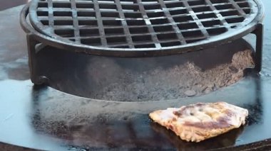 Eldivenli bir aşçı et kaburgalarını metal bir fırının üzerinde demir bir spatulayla çevirir.