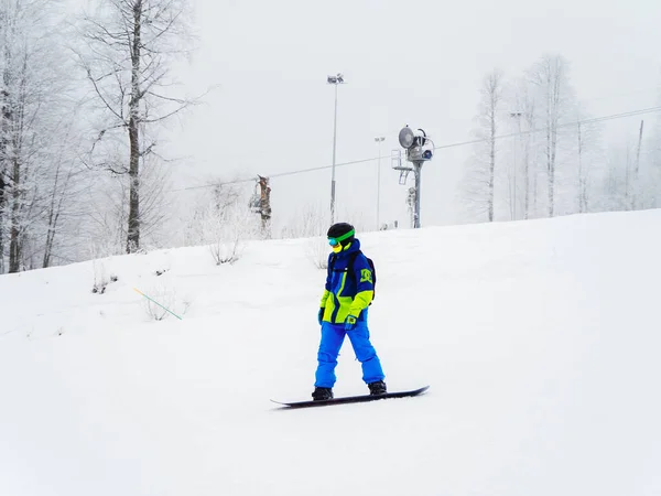 Russia, Sochi 21.01.2020. Snowboarder in tuta blu sta guidando lungo la pista con tempo nebbioso — Foto Stock