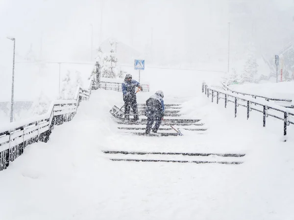 İşçiler yoğun kar yağarken merdivenlerden kar küreklerler. — Stok fotoğraf