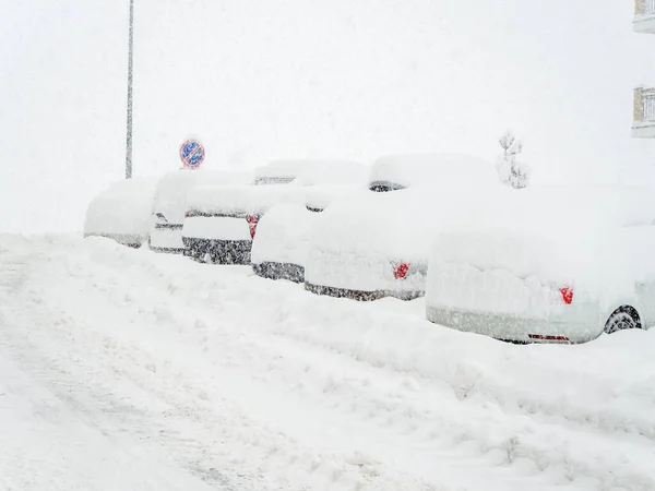Sněhem pokrytá silnice s auty zaparkovanými podél ní pokrytá sněhem během zimního chladu a sněhové bouře — Stock fotografie