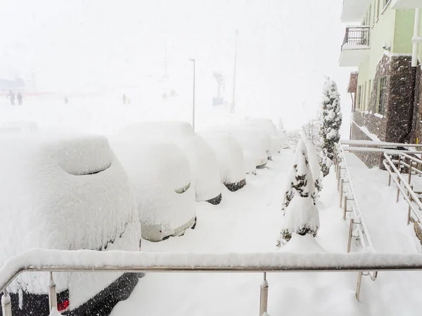 Hóval borított autók parkolnak az épület mentén sűrű ködben és nagy hóban. — Stock Fotó