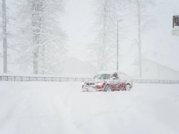 Şiddetli bir kar fırtınası sırasında araba karlı bir yolda gider. — Stok fotoğraf