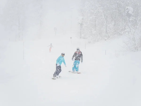 Les snowboarders roulent sur la piste en cas de fortes chutes de neige et de mauvaise visibilité — Photo