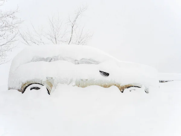 Carro coberto de neve fica na neve durante uma forte queda de neve — Fotografia de Stock