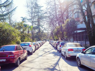 Rusya, Soçi 18.02.2020. Arabalar yol kenarında dar bir yolda park edilmiş, ağaçlar da konutun yanında.
