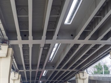 Gri bir demir otomobil üst geçidinin beton desteklerle alt görüntüsü